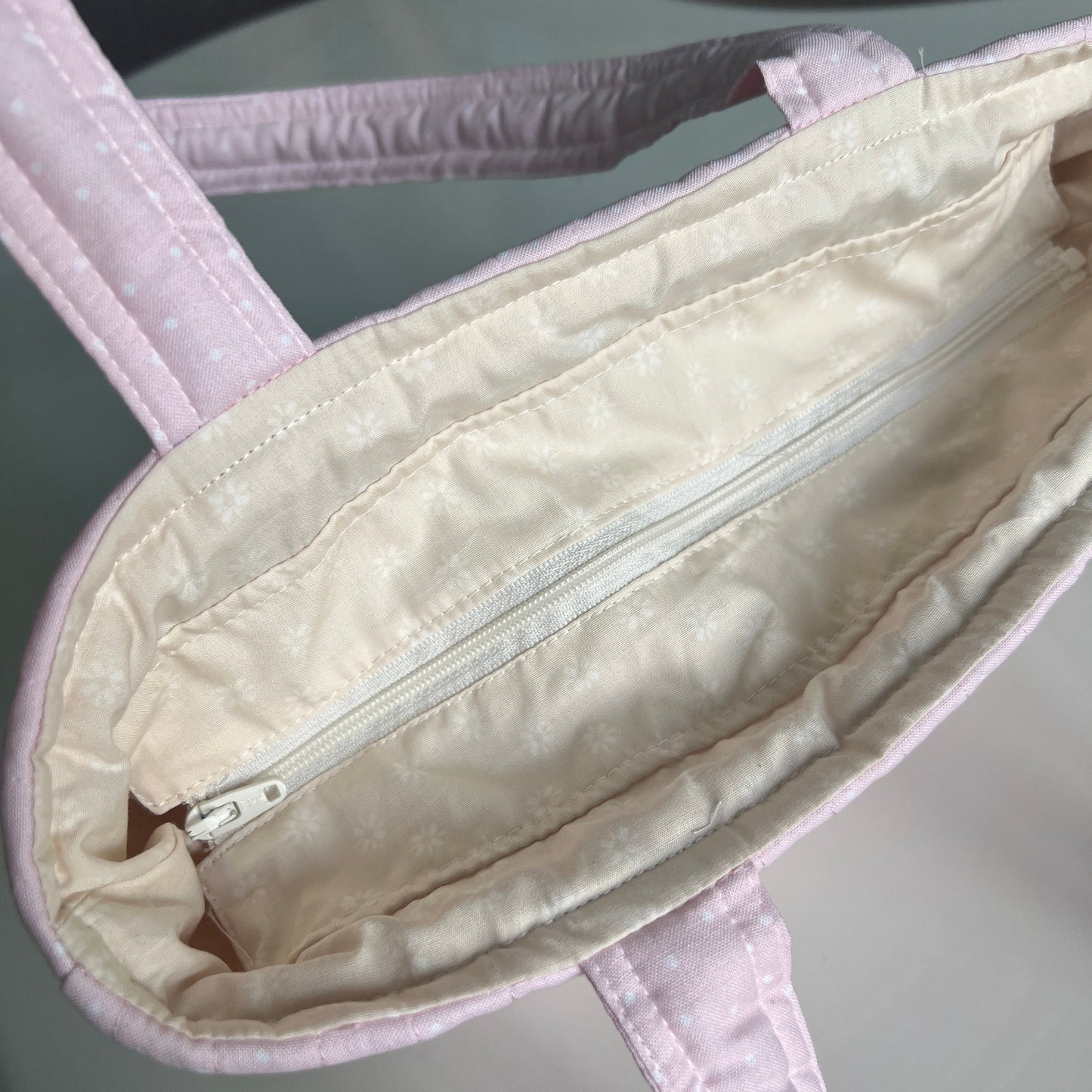 Close-up of a white baby carrier with a zipper on a gray background