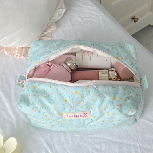 Baby doll in a blue pouch on a bed with a white nightstand in the background